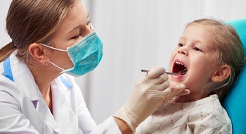 A dentist examining a little girl’s mouth