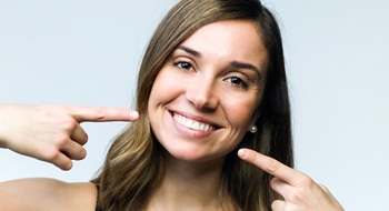 A young female pointing to her smile